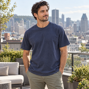 American Apparel 1301GD in Faded Navy, a stylish man aged 32 at an upscale Montreal rooftop terrace with a softly blurred urban skyline; illustrative lifestyle mockup