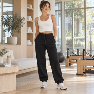 American Apparel RF491 in Black, a stylish woman aged 29 at a bright contemporary Pilates studio lounge with white oak and glass; illustrative lifestyle mockup