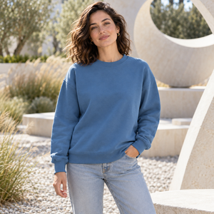 American Apparel RF496 in Sea Blue, a stylish woman aged 30 at a modern outdoor sculpture garden with light stone and softly blurred grasses; illustrative lifestyle mockup