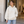 American Apparel RF498 in Bone, a stylish woman aged 29 at a contemporary gallery entrance with ivory stone and pale oak, warm natural daylight; illustrative lifestyle mockup