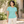 ATC ATC1000L True Celadon women's cotton T-shirt — premium sunlit botanical courtyard with subtle green foliage and textured cream walls lifestyle photograph