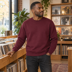 ATC ATCF2400 Maroon unisex crewneck sweatshirt — premium independent record shop with warm timber shelves and soft window light lifestyle photograph