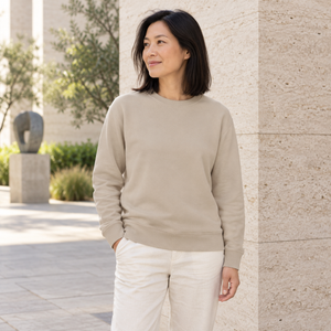 ATC ATCF2400 Sand unisex crewneck sweatshirt — premium calm modern gallery courtyard with textured limestone lifestyle photograph