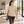 Woman wearing the CSW 24/7 Sprint S05650 T-shirt in Sand while carrying a yoga mat in a modern Pilates studio