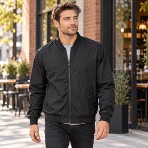 Model wearing the Independent Trading Co. Embroidered Lightweight Bomber Jacket in a lifestyle setting - Black