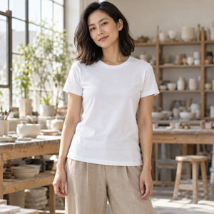 Woman wearing the M&O 4513 Fine White crewneck T-shirt in a sunlit ceramics workshop