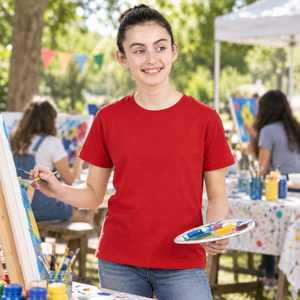 Next Level 3310 Youth Cotton Tee in Red — 13-year-old girl at an outdoor community art workshop