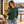 Next Level 3601 Unisex Cotton Long Sleeve Tee in Forest Green — woman reading on a wooden lakeside deck in early autumn