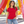 Next Level 3900 Women's Cotton Tee in Red — woman beside a bright contemporary public art installation