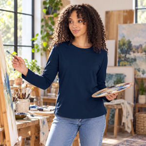 Next Level 3911 Women's Cotton Relaxed Long Sleeve Tee in Midnight Navy — woman painting in a sunlit home studio