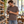 Next Level 6010 Unisex Triblend Tee in Macchiato — man inspecting analogue cameras in an independent camera shop
