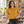 Next Level 7610 Women's Heavyweight Boxy Tee in Antique Gold — woman at an airy ceramics workshop with shelves of handmade objects