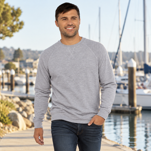Next Level 9000 Unisex Laguna Raglan Crewneck Sweatshirt in Heather Grey — man walking along a quiet marina on a cool morning