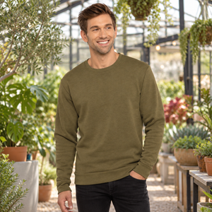 Next Level 9002 Unisex Malibu Crewneck Sweatshirt in Heather Military Green — man at a contemporary botanical greenhouse on a cool day
