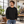 Next Level 9003 Unisex Santa Barbara Crewneck Sweatshirt in Black — man at a relaxed urban creative coworking loft