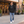 Next Level 9301 Unisex Laguna Hoodie Sweatshirt in Black/ Heather Grey — man outside an independent cinema with soft early-evening light